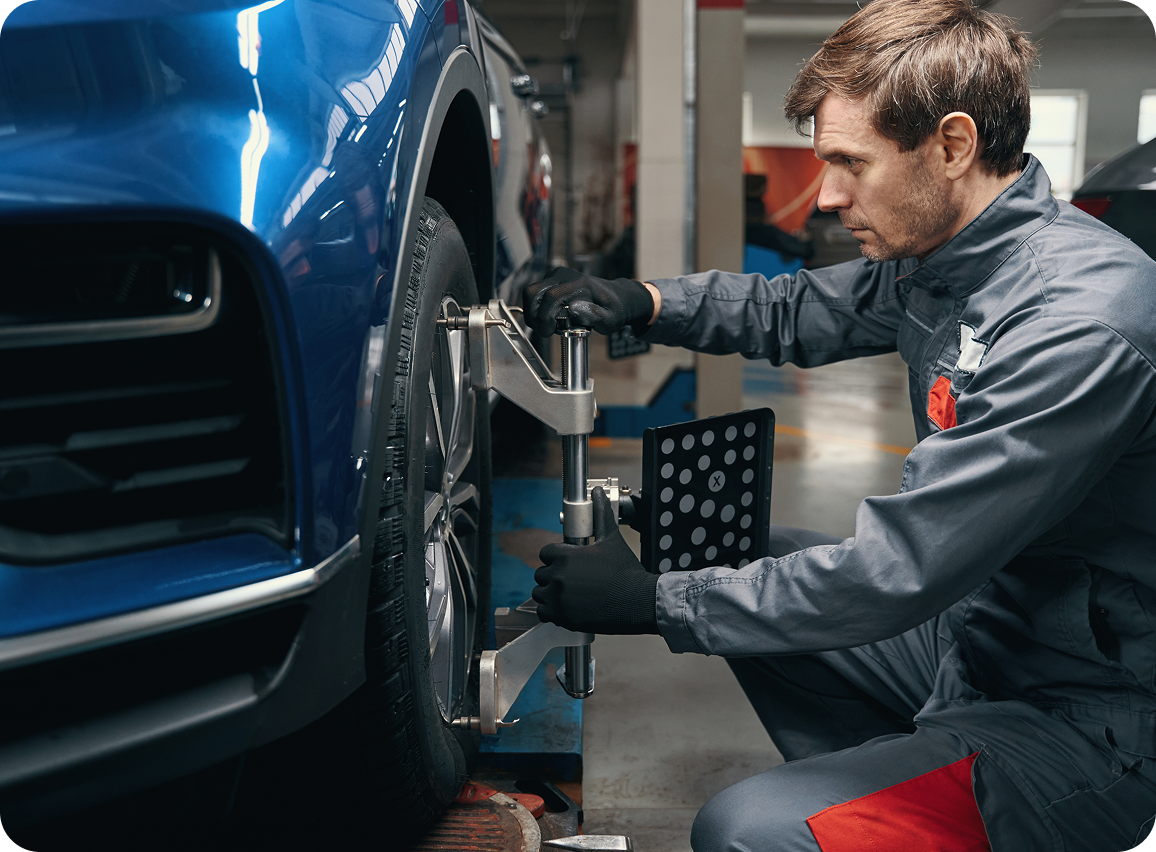 Mechanic aligning car wheel in garage